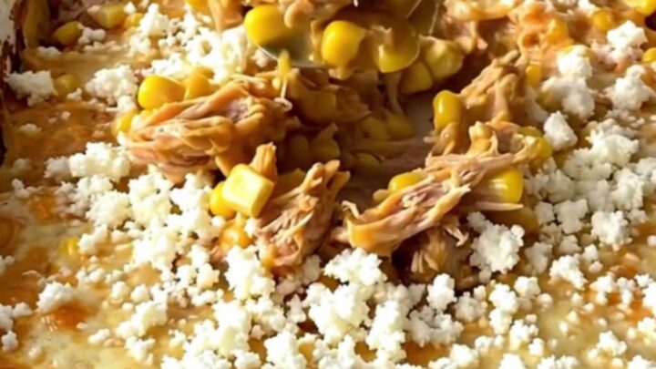 A top-down view of a golden, bubbling Mexican street corn turkey casserole in a white enamel baker.