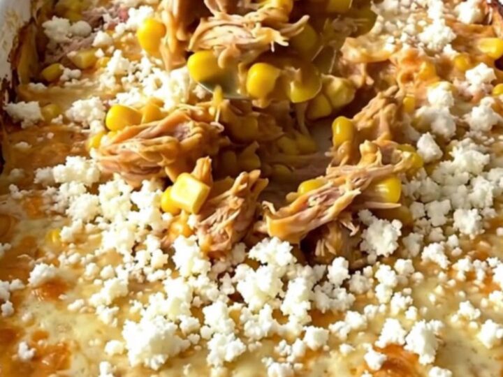 A top-down view of a golden, bubbling Mexican street corn turkey casserole in a white enamel baker.