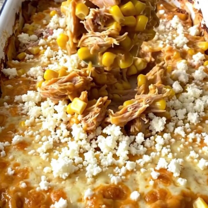 A top-down view of a golden, bubbling Mexican street corn turkey casserole in a white enamel baker.