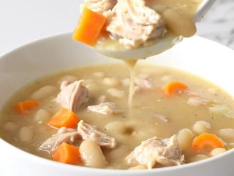 A bowl of creamy lemon pepper chicken and white bean soup with visible carrots.