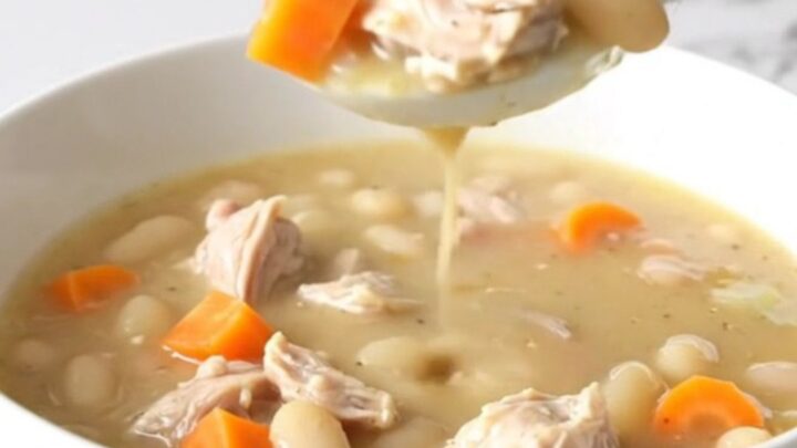 A bowl of creamy lemon pepper chicken and white bean soup with visible carrots.