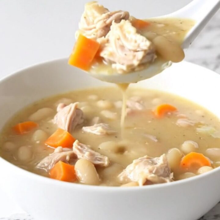 A bowl of creamy lemon pepper chicken and white bean soup with visible carrots.