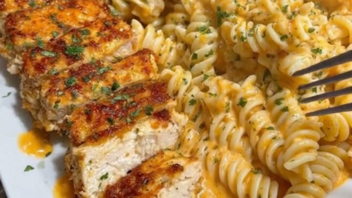 A close-up of steaming, rich cheese-coated rotini pasta with juicy