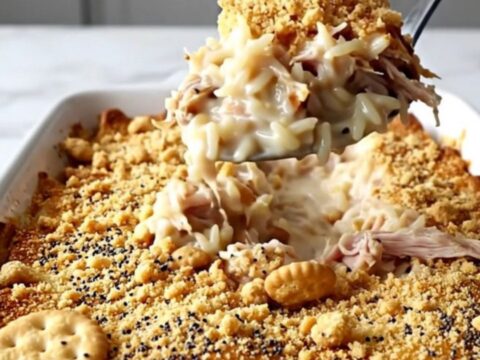 A golden-brown creamy turkey and rice casserole in a white baking dish with a crispy poppy seed cracker topping.