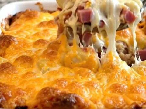 A top-down view of a creamy gnocchi and ham bake in a white ceramic dish with a golden melted cheddar crust.