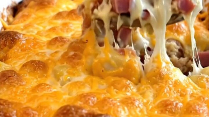 A top-down view of a creamy gnocchi and ham bake in a white ceramic dish with a golden melted cheddar crust.
