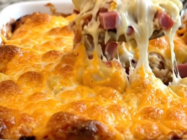 A top-down view of a creamy gnocchi and ham bake in a white ceramic dish with a golden melted cheddar crust.
