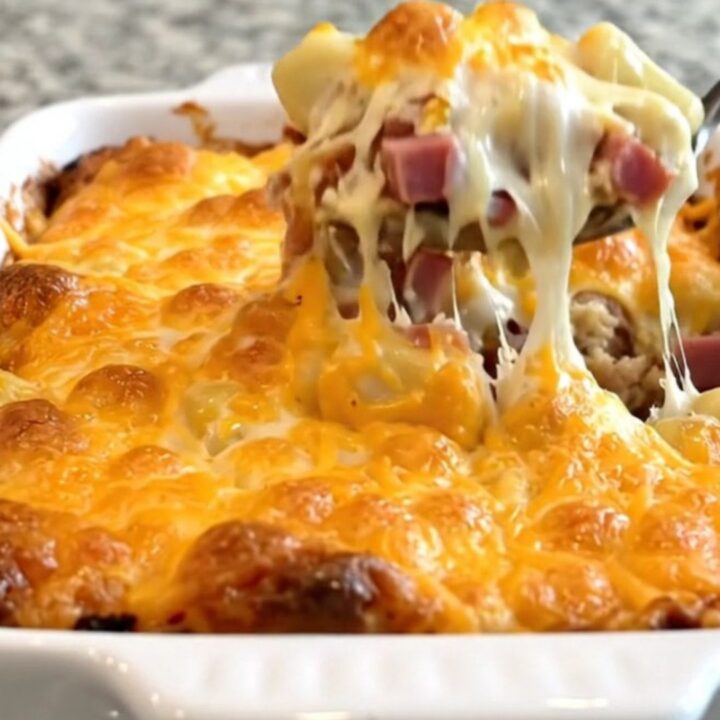 A top-down view of a creamy gnocchi and ham bake in a white ceramic dish with a golden melted cheddar crust.