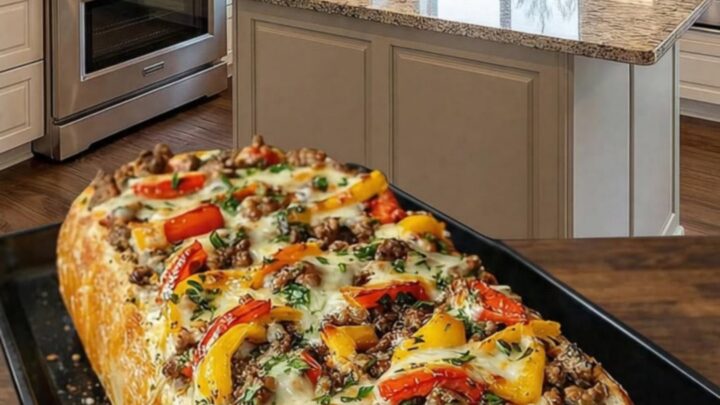 A crispy, golden-brown loaf stuffed with savory ground beef and peppers, topped with bubbly, melted mozzarella cheese.