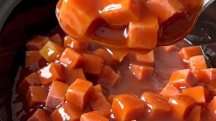 A close-up of slow cooker sweet and sour ham with vibrant pineapple chunks and green peppers in a glossy sauce.