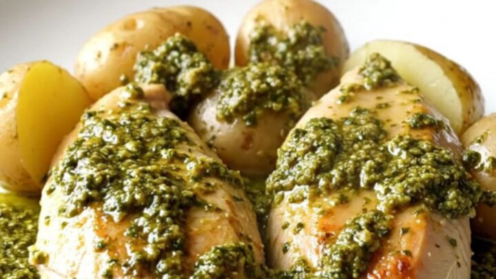 A slow cooker filled with tender chicken breasts and golden baby potatoes coated in a thick, vibrant green pesto sauce.