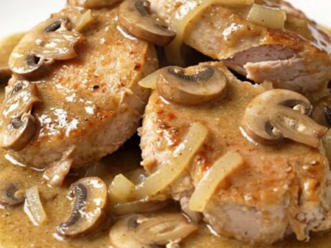 A close-up of creamy slow cooker turkey stroganoff with mushrooms and onions served on a white plate.
