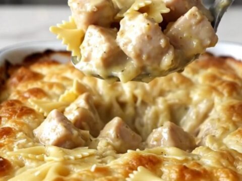 A large rectangular baker filled with creamy garlic butter bowtie pasta and cooked chicken pieces.