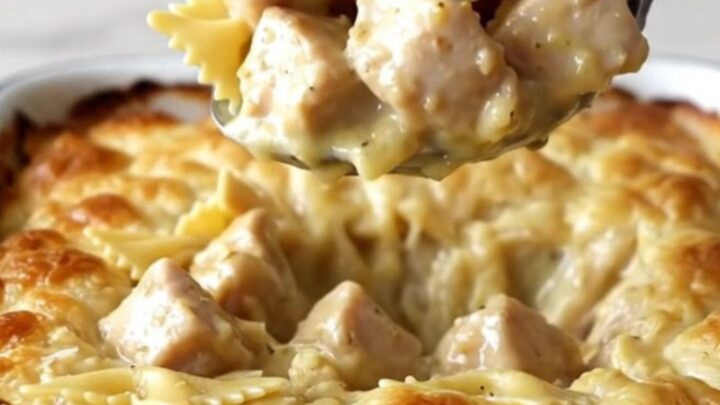 A large rectangular baker filled with creamy garlic butter bowtie pasta and cooked chicken pieces.
