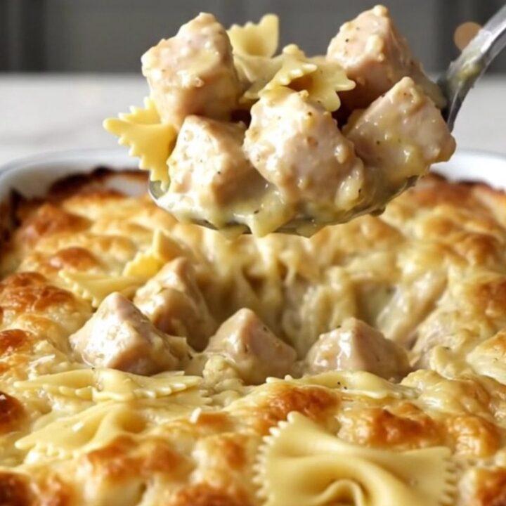 A large rectangular baker filled with creamy garlic butter bowtie pasta and cooked chicken pieces.
