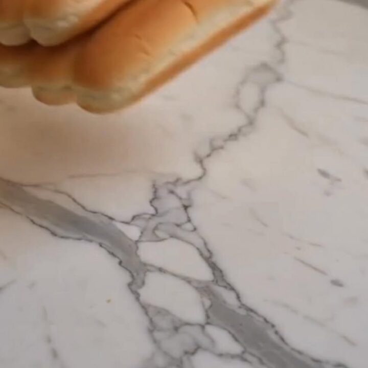 A close-up shot of a baked chili dog being pulled apart, showcasing a dramatic stretch of melted cheddar cheese and steaming
