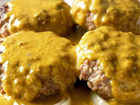 A close-up of creamy beer cheese turkey burger steaks served on a white plate.