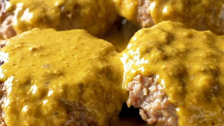 A close-up of creamy beer cheese turkey burger steaks served on a white plate.
