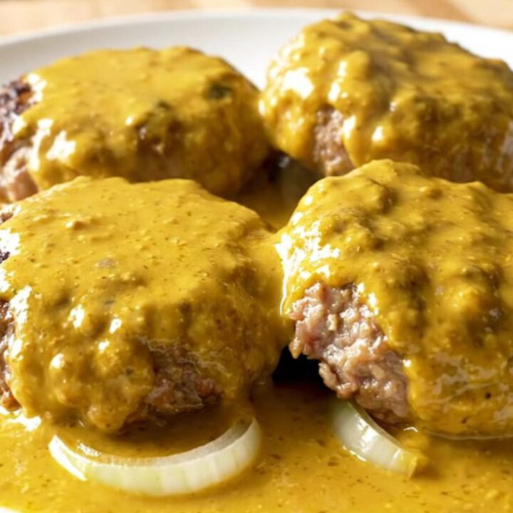 A close-up of creamy beer cheese turkey burger steaks served on a white plate.