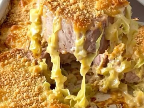 A rustic ceramic baking dish filled with tender pork chops and creamed cabbage, topped with a golden, crispy cracker crust.