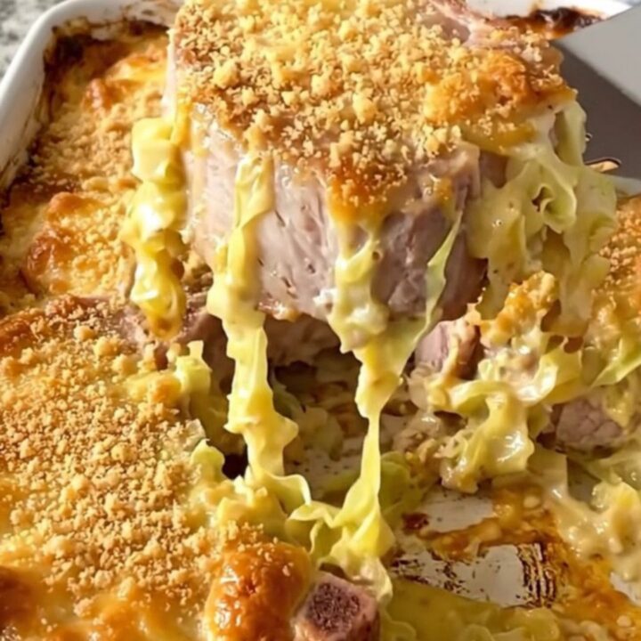 A rustic ceramic baking dish filled with tender pork chops and creamed cabbage, topped with a golden, crispy cracker crust.