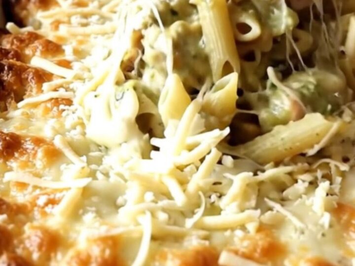 A bubbly, golden brown creamy salsa verde turkey penne bake in a white ceramic dish on a beige counter.