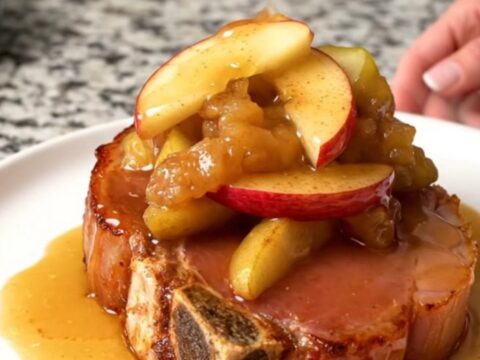 A thick, bone-in ham steak in a slow cooker topped with fanned red apple wedges and a cinnamon sugar glaze.