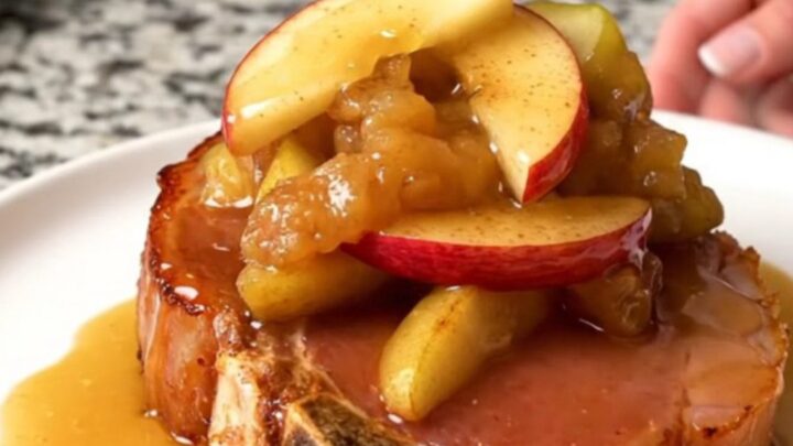 A thick, bone-in ham steak in a slow cooker topped with fanned red apple wedges and a cinnamon sugar glaze.
