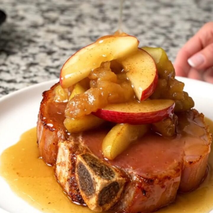 A thick, bone-in ham steak in a slow cooker topped with fanned red apple wedges and a cinnamon sugar glaze.