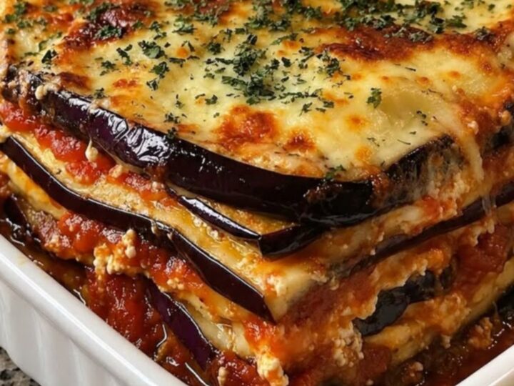 A slice of baked eggplant lasagna with melted mozzarella and tomato sauce on a white plate.