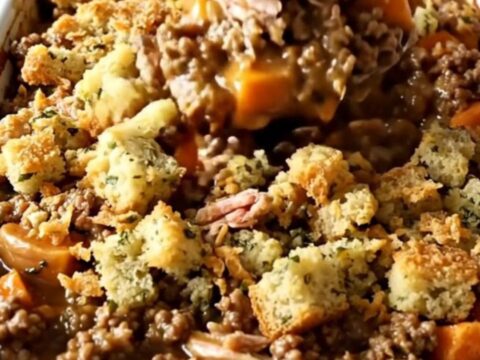 A top-down view of a rectangular ceramic baking dish filled with a golden, bubbling turkey, sweet potato, and stuffing bake.