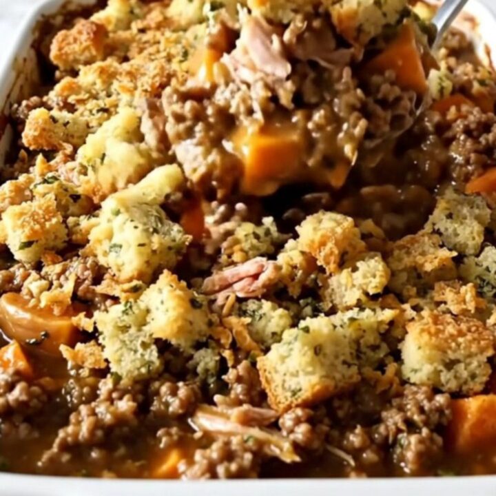 A top-down view of a rectangular ceramic baking dish filled with a golden, bubbling turkey, sweet potato, and stuffing bake.