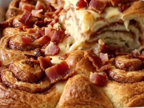 A golden, puffed maple bacon cinnamon roll bake in a white ceramic dish.