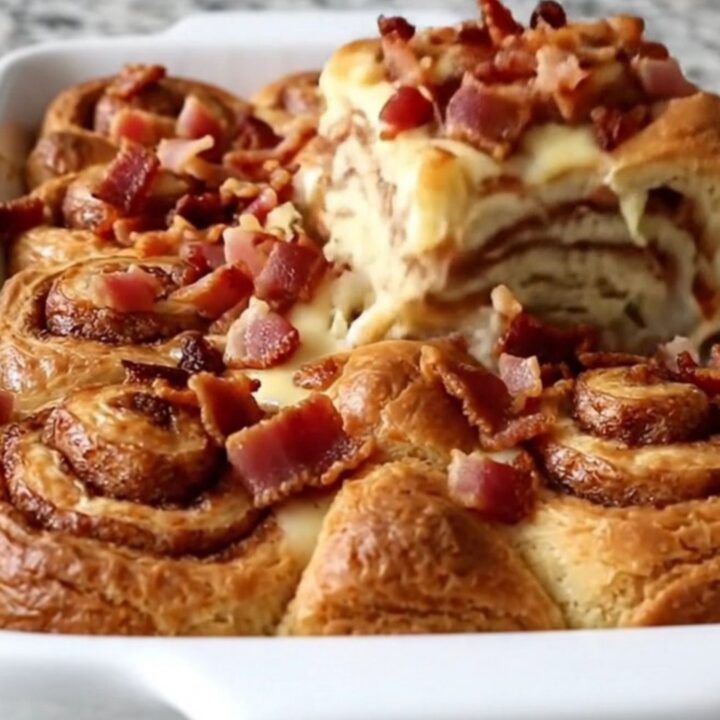 A golden, puffed maple bacon cinnamon roll bake in a white ceramic dish.