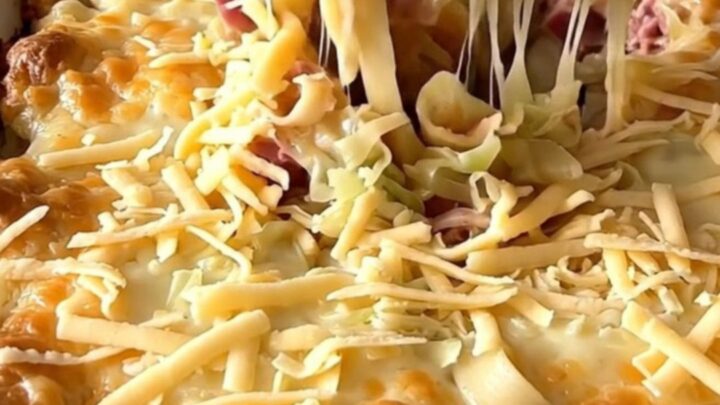 A top-down view of a Reuben noodle bake in a rectangular white ceramic dish, showing layers of noodles, corned beef