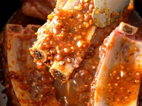 A close-up of tender, slow-cooked pork spareribs coated in a glistening, sticky chili lime glaze.