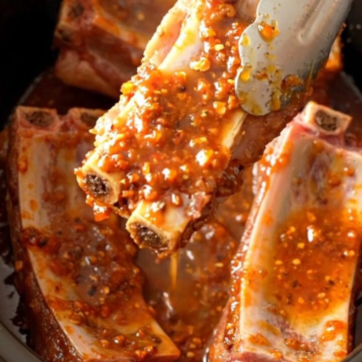 A close-up of tender, slow-cooked pork spareribs coated in a glistening, sticky chili lime glaze.