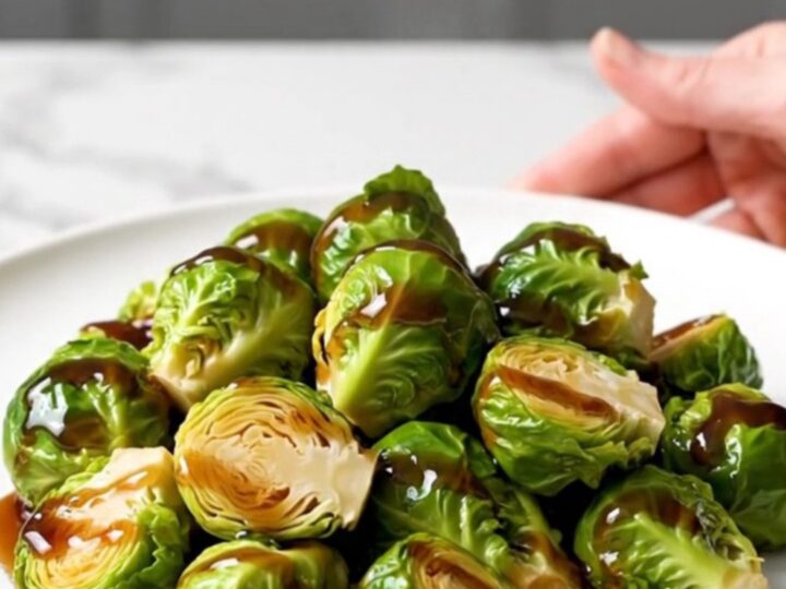 A top-down view of halved Brussels sprouts in a black slow cooker insert, seasoned and ready to cook.