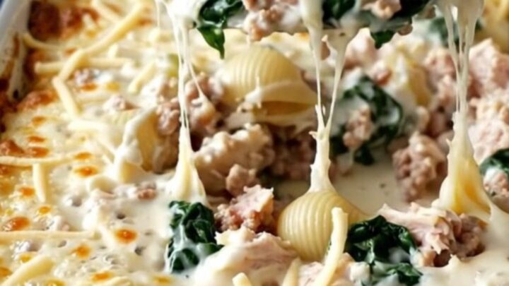 A top-down view of a rectangular white baking dish filled with pasta shells, ground turkey, and spinach in a creamy sauce.