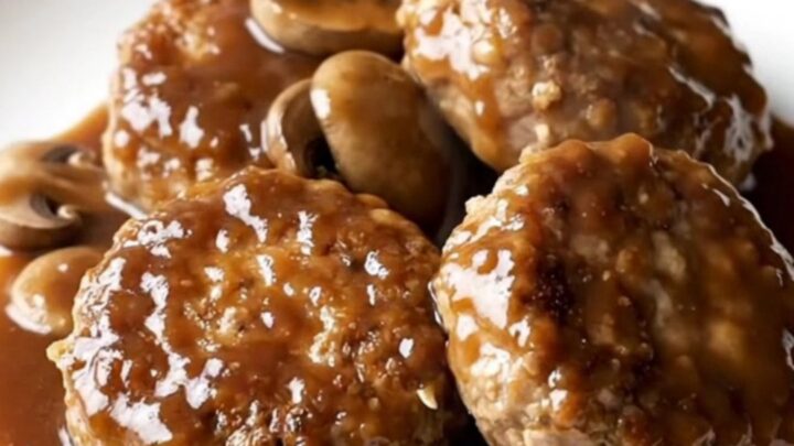A plate featuring a thick, juicy turkey burger steak covered in a rich mushroom and dark steak sauce gravy.