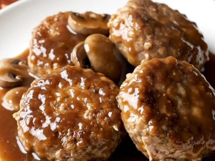 A plate featuring a thick, juicy turkey burger steak covered in a rich mushroom and dark steak sauce gravy.
