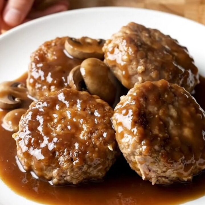 A plate featuring a thick, juicy turkey burger steak covered in a rich mushroom and dark steak sauce gravy.