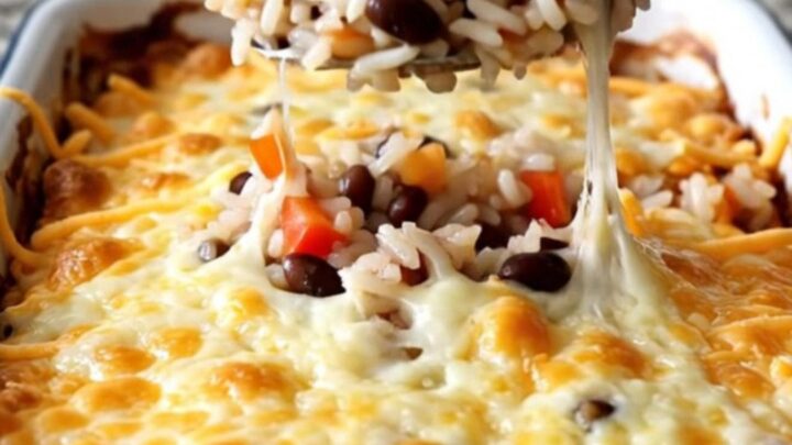 A golden, bubbling black bean and rice casserole in a white baking dish on a kitchen counter.