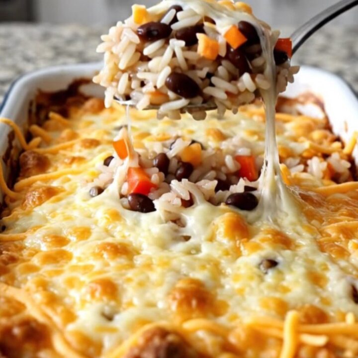 A golden, bubbling black bean and rice casserole in a white baking dish on a kitchen counter.