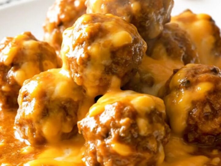 A close-up of delicious chili cheese meatballs served in a white bowl with melted cheese.