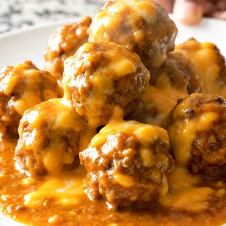 A close-up of delicious chili cheese meatballs served in a white bowl with melted cheese.
