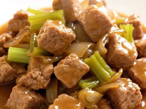A close-up of a bowl filled with slow-cooked pork chop suey featuring tender pork, sliced celery