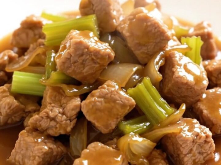 A close-up of a bowl filled with slow-cooked pork chop suey featuring tender pork, sliced celery