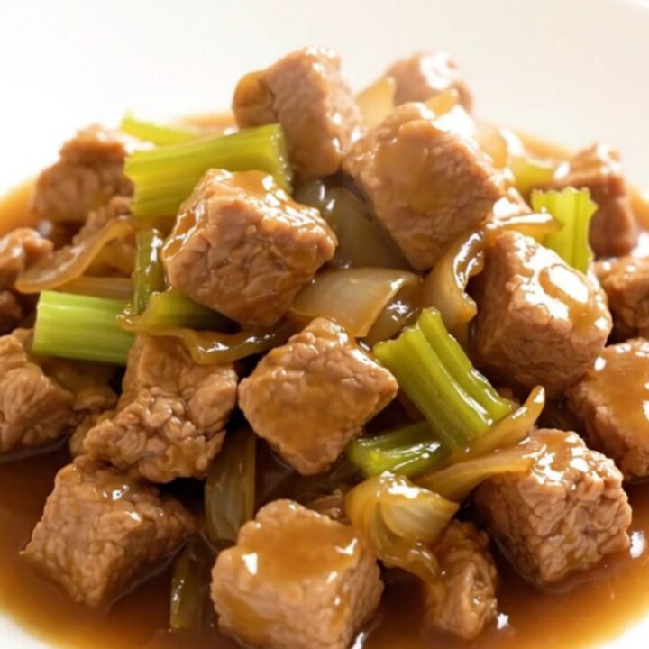 A close-up of a bowl filled with slow-cooked pork chop suey featuring tender pork, sliced celery