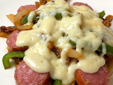 A close-up of slow cooker Philly sausage and peppers topped with melted provolone cheese.